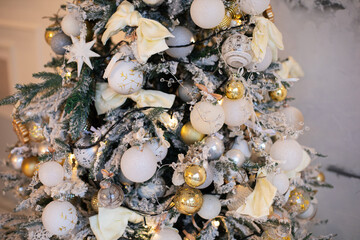 snow Christmas tree stands at home against white wall with golden balloon toys