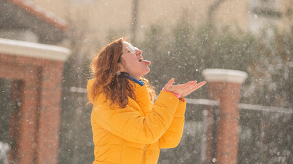 Obraz premium Red-haired Caucasian woman rejoices in winter and catches snowflakes with tongue.