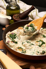 Delicious small meatballs with spinach in a creamy sauce in the frying pan