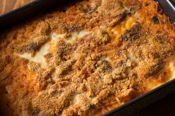 Vegan baked rice in baking dish on wooden background.