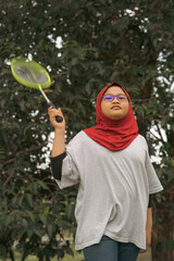 Young hijab Asian girl with badminton racket at the park.