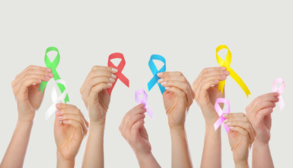 Many hands holding different ribbons on grey background. World Cancer Day
