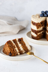 Homemade carrot cake with cream, blueberries, walnuts and spices on the table.