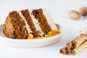 Piece of carrot cake with coconut cream, walnuts and cinnamon on a plate. Sugar, gluten and lactose free and vegan.