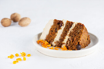 A piece of carrot cake with coconut cream, walnuts on a plate. Sugar, gluten and lactose free and vegan.