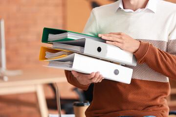 Young man with folders in office
