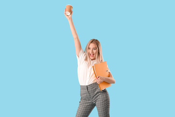 Happy young woman with folder and cup of coffee on blue background