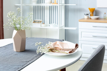 Beautiful table setting with vase and gypsophila flowers in dining room