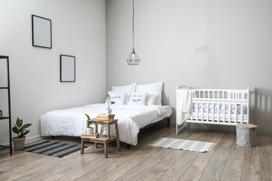 Interior of light bedroom with crib and blank frames