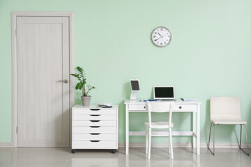 Interior of doctor's office with modern workplace and chest of drawers