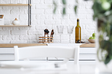 Empty glasses and bottle of wine on kitchen counter near white brick wall