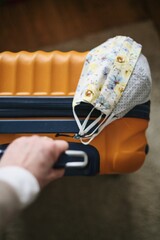 Planning a trip during a pandemic - orange suitcase and masks