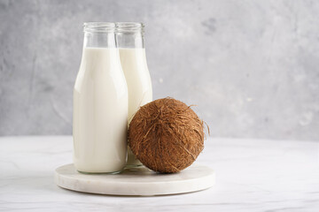 Two bottles with non-dairy milk and coconut on round marble board