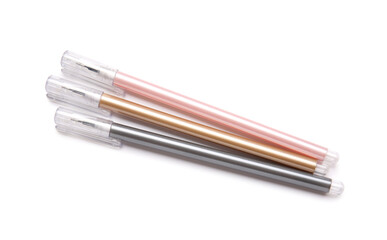 Pink, golden and black pens on white background