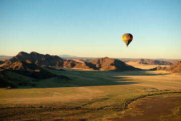 A horizontal shot of a hot air balloon flight over the Sossusvlei National Park landscape at sunrise, Namibia