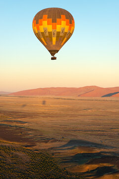 A vertical shot of a hot air balloon flying over the Sossusvlei landscape at sunrise, Namibia