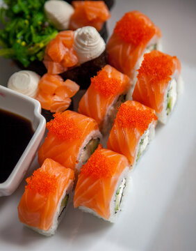 Salmon sushi set. Sushi roll Philadelphia with red fish, salmon, red caviar. Roll with soft avocado and cream cheese under a layer of massago caviar. Classic sushi. Food background