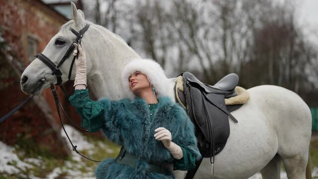 graceful lady and white horse outdoors in winter day, beautiful woman is posing with steed
