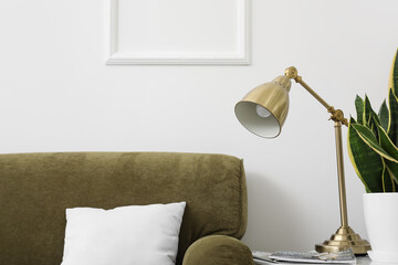 Golden lamp with magazines and houseplant in stylish living room