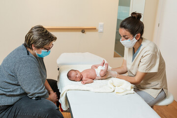 Female physiotherapist doing an evaluation of the primary respiratory movement in a newborn baby. - obrazy, fototapety, plakaty
