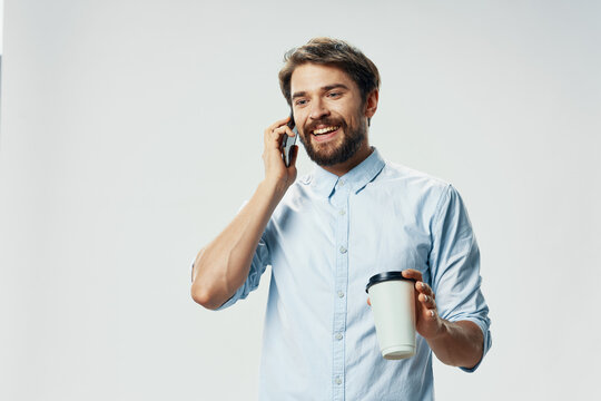 bearded man in shirt talking on the phone cup of coffee