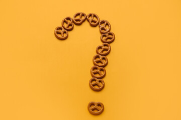 Question mark made of mini pretzels on orange background