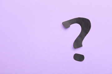 Question mark made of black paper on lilac background