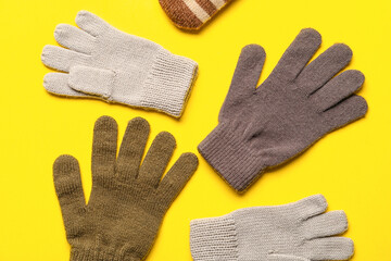 Different warm mittens on yellow background, closeup