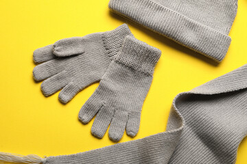 Warm gloves, hat and scarf on yellow background