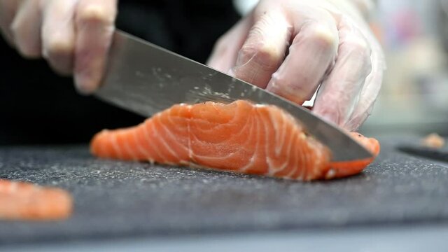 Crop chef cutting fresh salmon