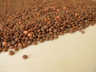 Brown mountain lentils distributed flatly on a wooden board