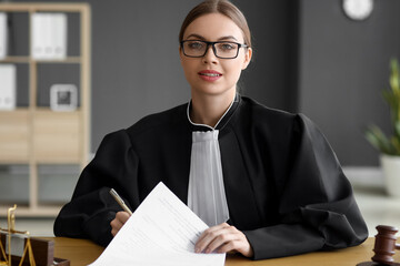 Female judge signing documents at workplace in courtroom