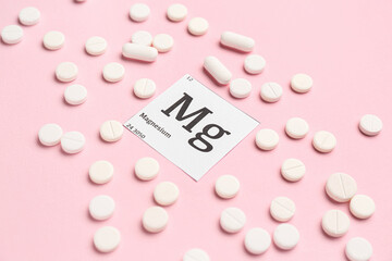 Magnesium pills on pink background, closeup