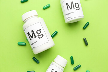 Bottles of magnesium pills on green background