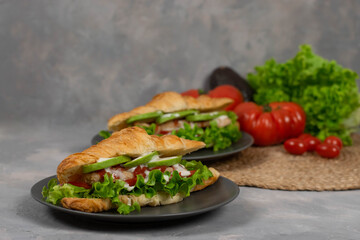 Croissant sandwich with turkey ham, tomatoes, cheese and lettuce salad. Continental style breakfast