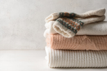 Stack of knitted sweaters and socks on white table