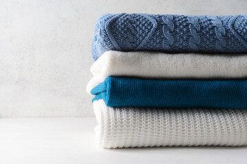 Stack of knitted sweaters on white table