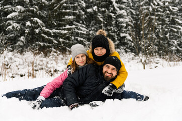 Happy family have fun in winter forest and looking at camera. Mother, father and son playing with snow. Family Christmas concept. Enjoying spending time together