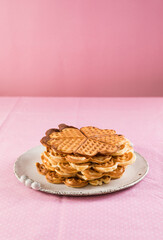 Freshly baked homemade heart shaped Belgium waffles on gray background. European baked pastry sweets. St. Valentine's Day breakfast concept.