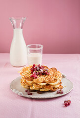 Freshly baked homemade heart shaped Belgium waffles with currant jam on pink background. European baked pastry sweets. St. Valentine's Day breakfast concept.