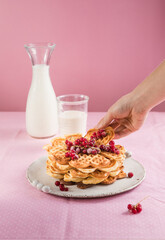 Freshly baked homemade heart shaped Belgium waffles with currant jam on pink background. European baked pastry sweets. St. Valentine's Day breakfast concept.