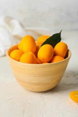 Bowl with tasty kumquat fruits  on light background