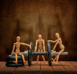 Wooden men Gestalta play sports with a cheerful company, on a wooden table and an artistic background.