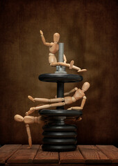 Wooden men Gestalta play sports with a cheerful company, on a wooden table and an artistic background.