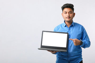 Young indian man showing laptop screen on white background.