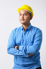 Young Indian engineer wearing yellow color hard hat and giving successful gesture.