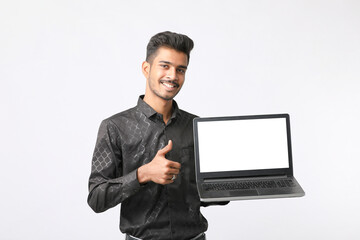 Young indian man showing laptop screen on white background.