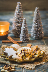 Christmas cookies on a star shaped plate with christmas decoration and candle light, vertical