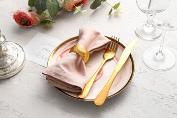 Beautiful table setting with wedding invitation on light background