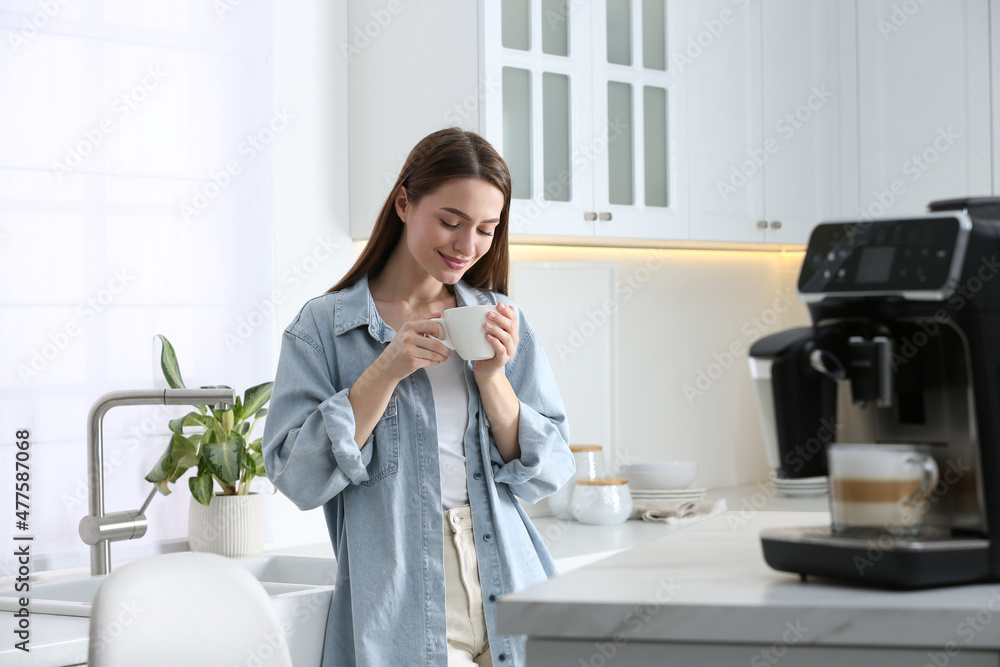 Canvas Prints young woman enjoying fresh aromatic coffee near modern machine in kitchen